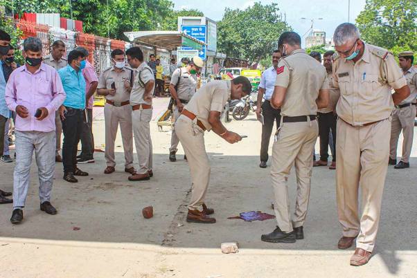 गुरुग्राम में शीतला माता मंदिर के गेट के बाहर एक व्यक्ति की गोली मारकर हत्या के बाद जांच करती पुलिस