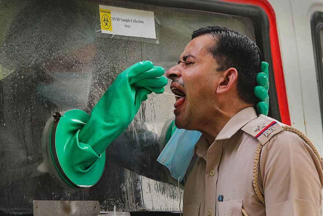 गुरुग्राम में एक पुलिस कर्मचारी के कोरोना वायरस टेस्ट के लिए स्वैब टेस्ट का सैंपल लेता एक स्वास्थ्य कर्मचारी। कोरोना संकट के बीच ड्यूटी करने के चलते पुलिस कर्मियों पर संक्रमण का काफी खतरा रहता है।