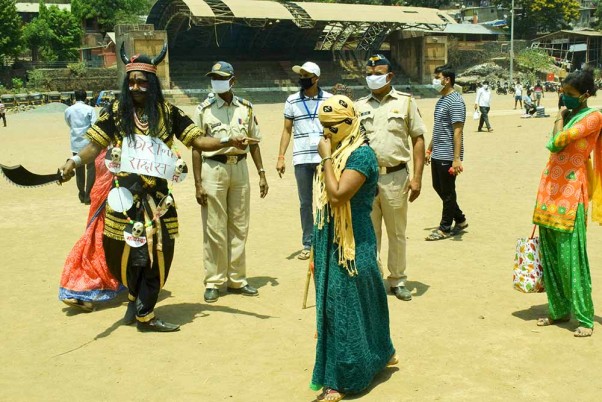 लॉकडाउन के बीच मुंबई के घाटकोपर में कोरोना राक्षस के रूप में लोगों से अपने घरों के अंदर रहने का आग्रह करता एक शख्स