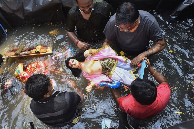 नई दिल्ली में दुर्गा पूजा उत्सव के अंतिम दिन देवी दुर्गा की मूर्ति का विसर्जन करते भक्त