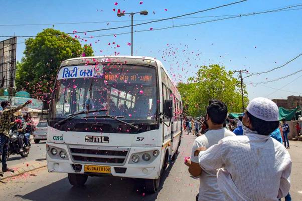 कोरोना वायरस के प्रसार पर अंकुश लगाने के लिए लगाए गए लॉकडाउन के बीच कोविड -19 के ठीक हुए मरीजों को ले जाने वाली बस पर फूल बरसाते लोग