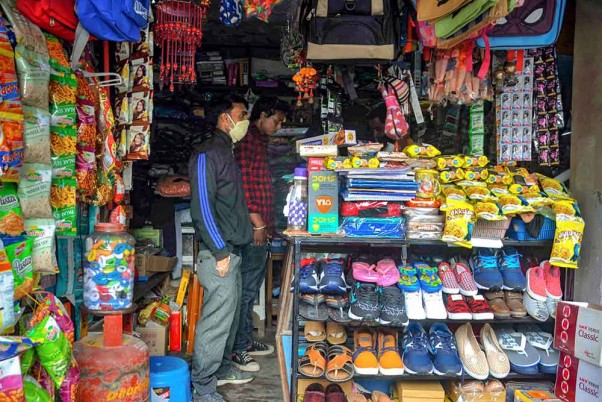 कोरोना वायरस के प्रसार पर अंकुश लगाने के लिए लगाए गए लॉकडाउन के बीच खोली गई दुकानों से आवश्यक सामान खरीदते ग्राहक