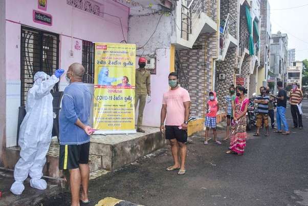 सूरत में कोविड-19 टेस्ट के लिए लोगों के नमूने एकत्र करते चिकित्साकर्मी, लाइन में लगकर अपनी बारी इंतजार करते स्थानीय