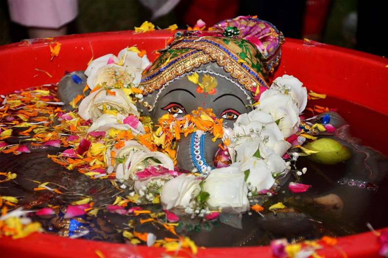अमृतसर में पानी से भरे टब में भगवान गणेश की मिट्टी से बनी मूर्ति का विसर्जन करते भक्त