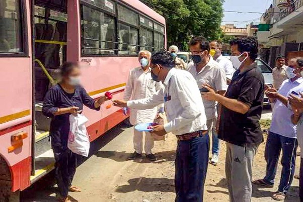 हिसार में 59 वर्षीय कोरोना मरीज बिमला के स्वस्थ होने के बाद घर लौटने पर महिला का स्वागत करते लोग