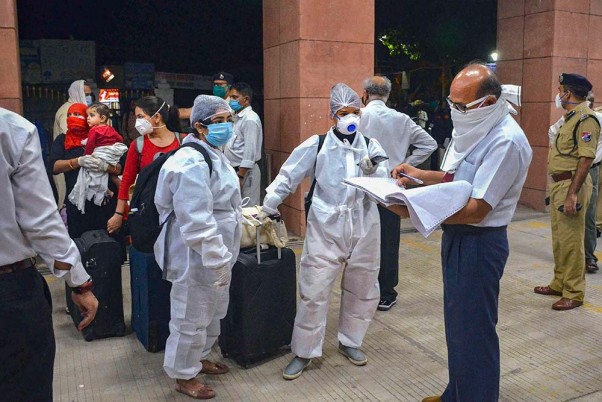 भोपाल में ट्रेन में चढ़ने से पहले रेलवे स्टेशन पर यात्रियों के दस्तावेजों की जांच करता एक रेलवे अधिकारी