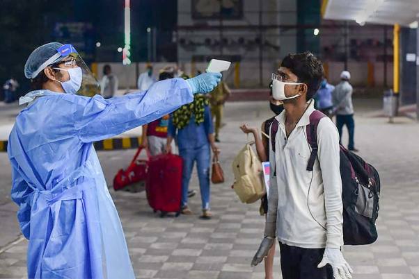 प्रयागराज जंक्शन पर एक ट्रेन में चढ़ने से पहले यात्रियों की थर्मल स्क्रीनिंग करते स्वास्थ्यकर्मी