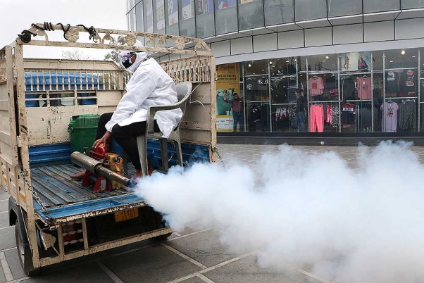 कोरोना वायरस के प्रकोप के मद्देनजर सड़कों पर धुंआ करता जम्मू नगर निगम (जेएमसी) का एक कर्मचारी