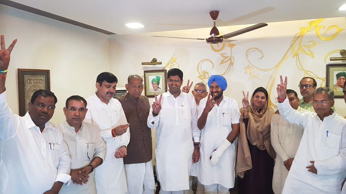 जननायक जनता पार्टी के विधायकों की बैठक में विजय संकेत दिखाते पार्टी के नेता दुष्यंत चौटाला