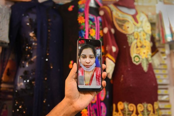 कोलकाता में लॉकडाउन के पांचवें चरण के दौरान वीडियो कॉलिंग के माध्यम से अपने ग्राहक को सामान दिखाता एक दुकानदार