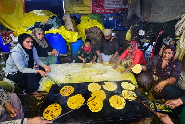 दिल्ली के सिंघु बॉर्डर्र पर नए कृषि कानूनों के खिलाफ प्रदर्शन कर रहे किसानों के लिए भोजन बनाती महिलाएं