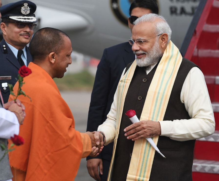 नेशनल गंगा काउंसिल की बैठक में शामिल होने के लिए कानपुर पहुंचे प्रधानमंत्री नरेंद्र मोदी का स्वागत करते उत्तर प्रदेश के मुख्यमंत्री योगी आदित्यनाथ