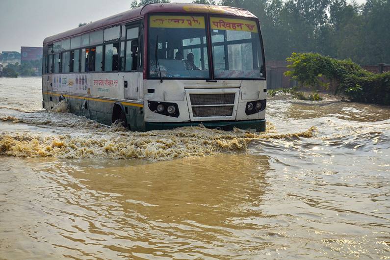 भारी बारिश के बाद मुरादाबाद में पानी से भरी सड़कों पर गुजरती बस