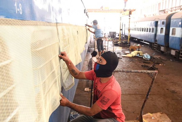 मुंबई के माटुंगा में कोविड-19 मरीज के लिए पुराने ट्रेन के कोच को आइसोलेशन वार्ड में बदलते कर्मचारी