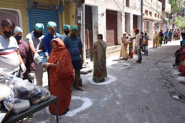 लॉकडाउन के बीच पटना में सोशल डिस्टेसिंग को ध्यान में रखते हुए सड़कों पर बनाए गोले में खड़े होकर खाने का सामान लेती महिलाएं