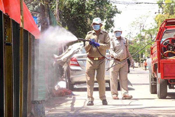 कोरोना वायरस के प्रसार पर अंकुश लगाने के लिए लगाए गए लॉकडाउन के दौरान नोएडा के सेक्टर-8 में कीटाणुनाशक का छिड़काव करते कर्मचारी