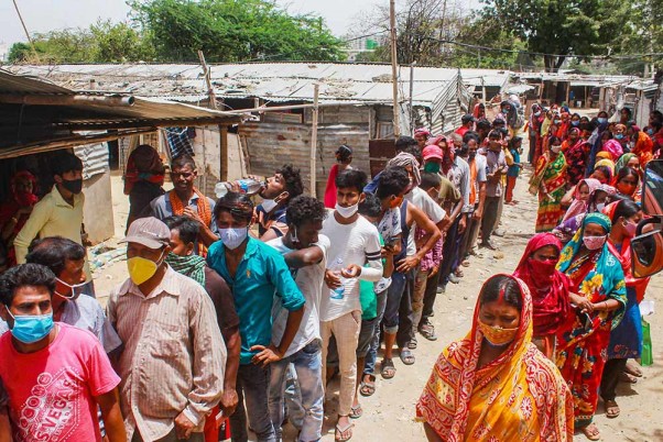 नेशनल डॉक्टर्स डे: गुरुग्राम के एक इलाके में कोविड-19 वैक्सीन लगवाने के लिए बिना सोशल डिस्टेंसिंग का पालन करते हुए लाइन में लगे लोग