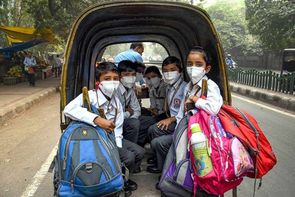 नई दिल्ली में वायु प्रदूषण से सुरक्षा पाने के लिए मास्क पहनकर स्कूल जाते छात्र