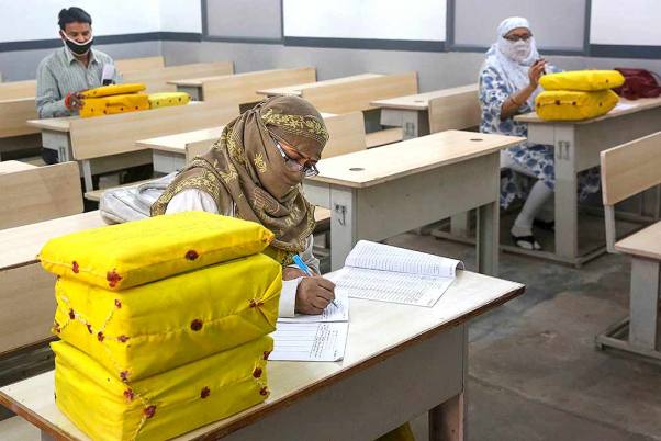 कोरोना वायरस के प्रसार को रोकने के लिए लगाए गए लॉकडाउन के बीच भोपाल में हायर सेकेण्डरी परीक्षाओं की उत्तर पुस्तिकाओं का मूल्यांकन करते शिक्षक