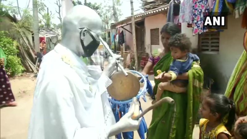 भुवनेश्वर में महात्मा गांधी के पोशाक में स्लम बस्तियों में मास्क और सेनेटाइजर बांटता एक आदमी