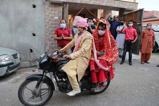 लॉकडाउन के बीच जम्मू में शादी के बाद मास्क पहनकर अपने घर जाते दूल्हा-दुल्हन