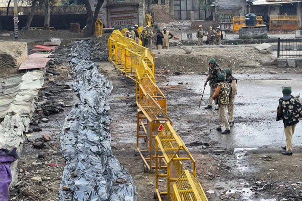 नई दिल्ली में सिंघु बॉर्डर पर बैरिकेड्स के पास सुरक्षाकर्मी का पहरा