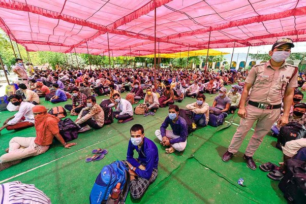 लॉकडाउन के दौरान राजधानी दिल्ली से अपने मूल स्थानों पर जाने के लिए एक कतार में बैठे बिहार के प्रवासी श्रमिक