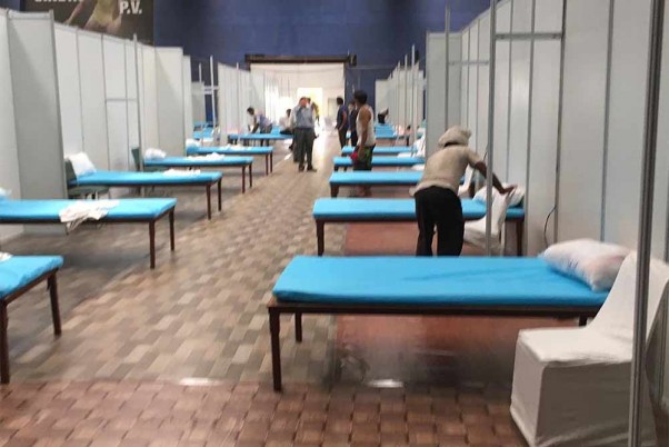 दिल्ली में कोरोना के बढ़ते मामलों के बीच राष्ट्रमंडल खेल गांव के इनडोर स्टेडियम में कोविड-19 केयर सेंटर बनाने का काम करते मजदूर