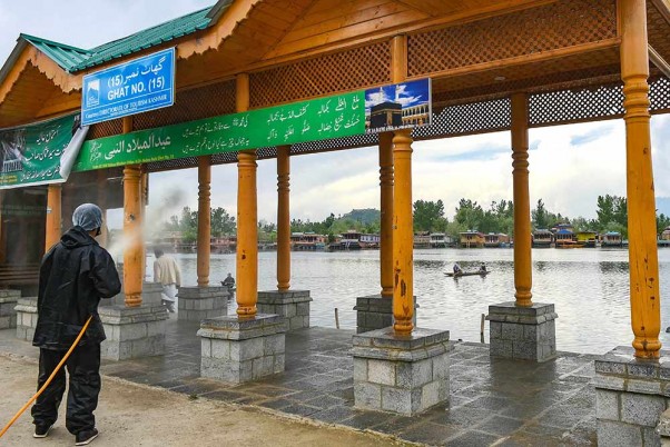 कोरोना के मद्देनजर श्रीनगर में लॉकडाउन  के दौरान डल झील के एक गेट पर कीटाणुनाशक का छिड़काव करता कर्मचारी