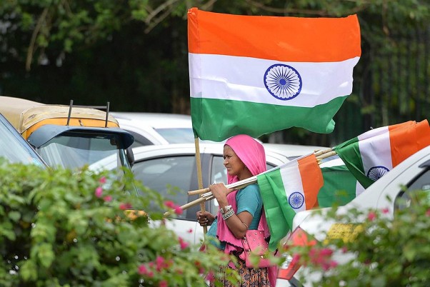 स्वतंत्रता दिवस से पहले नई दिल्ली में ट्रैफिक सिग्नल पर तिरंगे बेचती महिला