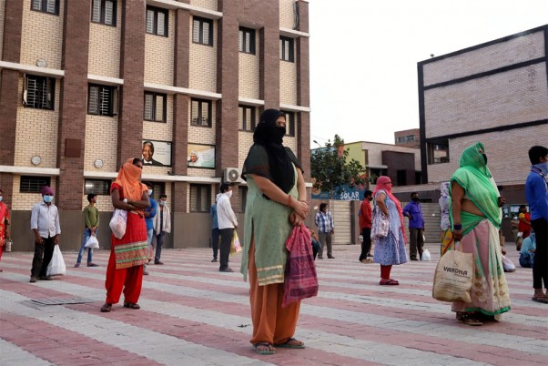 पूर्वी दिल्ली के एक स्कूल में बंट रहे भोजन सामग्री को लेने के लिए सामाजिक दूरी बनाकर कतार में खड़े लोग