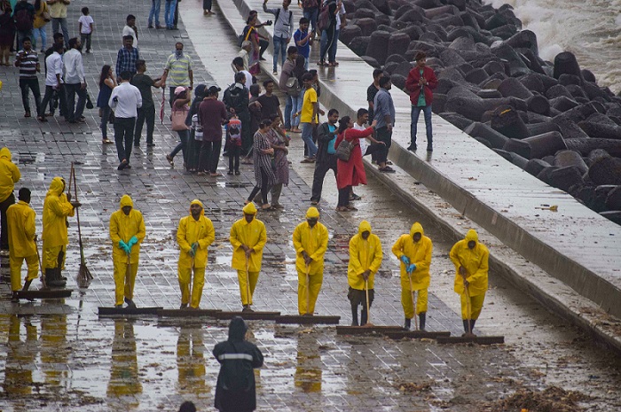 मुंबई  में हाई टाइड की चेतावनी के मद्देनजर मरीन ड्राइव के किनारे कूड़े-कचरे को साफ करते बीएमसी के कर्मचारी