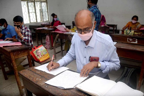 लॉकडाउन के बीच अगरतला में सोशल डिस्टेंसिंग का ध्यान रखते हुए दसवीं कक्षा की बोर्ड परीक्षा की उत्तर पुस्तिका जांचते शिक्षक