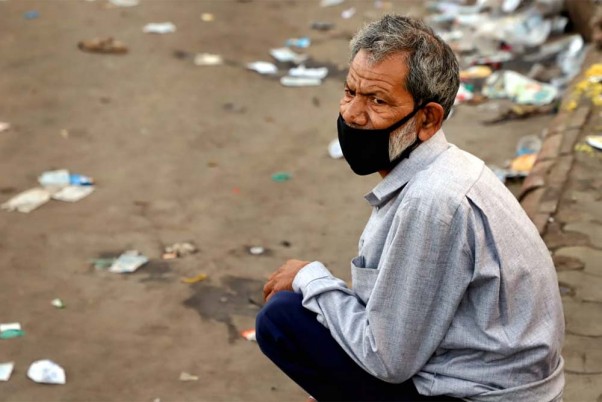 गाजियाबाद के कौशांबी में बस के इंतजार में आस लगाए बैठा एक प्रवासी श्रमिक