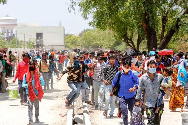 यूपी और बिहार में अपने घरों को लौटने के लिए रेलवे स्टेशन तक जाने के लिए वाहनों की प्रतीक्षा करते लॉकडाउन के बीच अहमदाबाद में फंसे प्रवासी श्रमिक