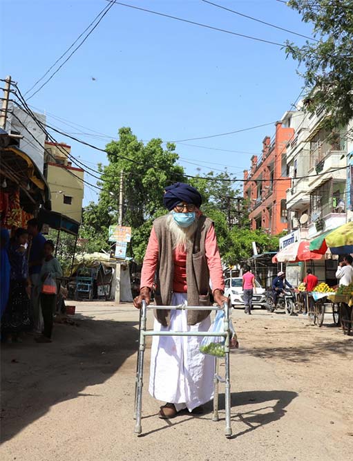 कोरोना महामारी के मद्देनजर लगाए गए लॉकडाउन के दौरान बाजार से सब्जियां और फल ले जाता एक वरिष्ठ नागरिक