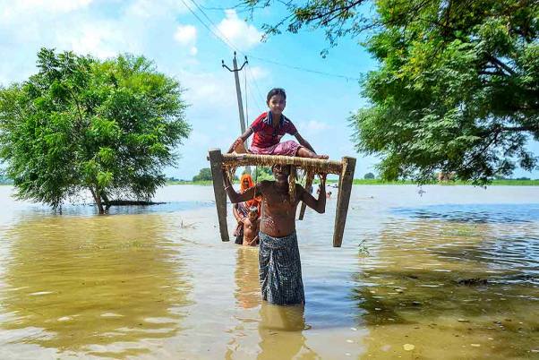 मिर्जापुर के नरसिंहपुर गांव में बारिश के बाद गंगा नदी के उफान पर होने के कारण सुरक्षित स्थान की ओर जाते ग्रामीण