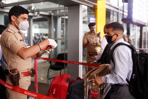 कोलकाता में एनएससीबीआई एयरपोर्ट पर कोरोनो वायरस से बचाव के लिए मास्क पहने सुरक्षाकर्मी और यात्री