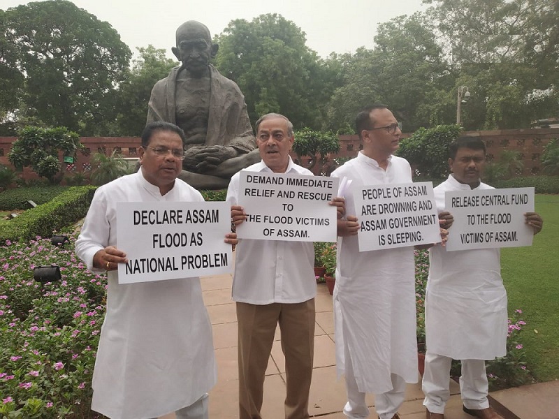 असम बाढ़ को राष्ट्रीय समस्या घोषित करने की मांग को लेकर संसद में गांधी प्रतिमा के सामने विरोध प्रदर्शन करते कांग्रेस सांसद