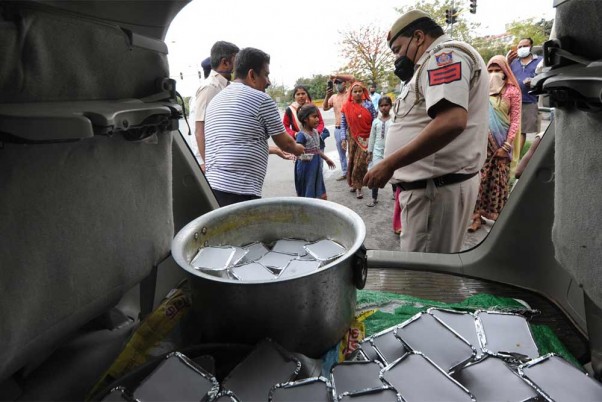 राजधानी दिल्ली में कोरोना वायरस महामारी के मद्देनजर लगाए गए राष्ट्रव्यापी बंद के दौरान बेघर लोगों को खाना बांटते वॉलंटियर्स और पुलिस अधिकारी