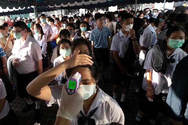 कोरोना वायरस के मद्देनजर थाईलैंड के एक स्कूल में छात्रों की जांच करता स्वास्थ्य अधिकारी