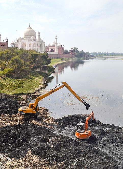 आगरा में अमेरिकी राष्ट्रपति डोनाल्ड ट्रंप की यात्रा से पहले ताजमहल के पास यमुना नदी के मलबे को साफ करता जेसीबी
