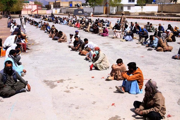 पाकिस्तान के क्वेटा में लॉकडाउन के दौरान सोशल डिस्टेंसिंग का ध्यान रखते हुए  भोजन के पैकेट का इंतजार करते बैठे लोग