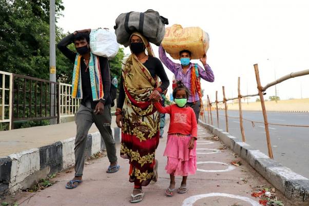 राजधानी दिल्ली में लॉकडाउन के दौरान सिर पर सामान लादे अपने घरों की ओर पैदल ही जाते प्रवासी श्रमिक