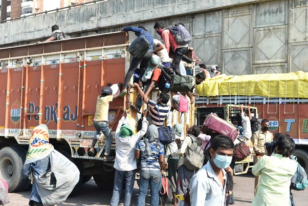 लॉकडाउन के दौरान लखनऊ-फैजाबाद सड़क मार्ग से अपने गृहनगर जाने के लिए एक ट्रक में चढ़ते प्रवासी मजदूर
