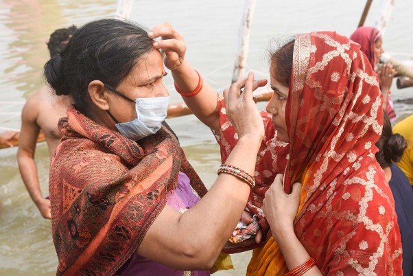 पटना में 'छठ' पर्व के अवसर पर 'खरना पूजा' के दौरान गंगा नदी में पवित्र डुबकी लगाने के बाद एक-दूसरे को सिंदूर लगाती महिलाएं