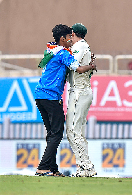 रांची के जेएससीए स्टेडियम में भारत और दक्षिण अफ्रीका के बीच तीसरे टेस्ट मैच के दौरान दक्षिण अफ्रीका के खिलाड़ी क्विंटन डी कॉक को गले लगाता एक शख्स