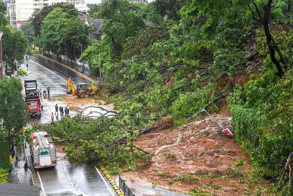 मुंबई में भारी बारिश के कारण हुए भूस्खलन के बाद सड़कों से मलबा हटाते नगर निगम के कर्मचारी