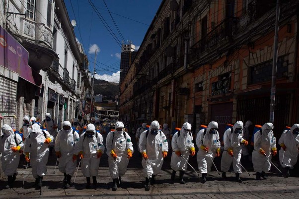 बोलिविया के ला पाज में कोरोना वायरस का संक्रमण रोकने के लिए शहर के एक मार्ग को सेनिटाइज करते कर्मचारी