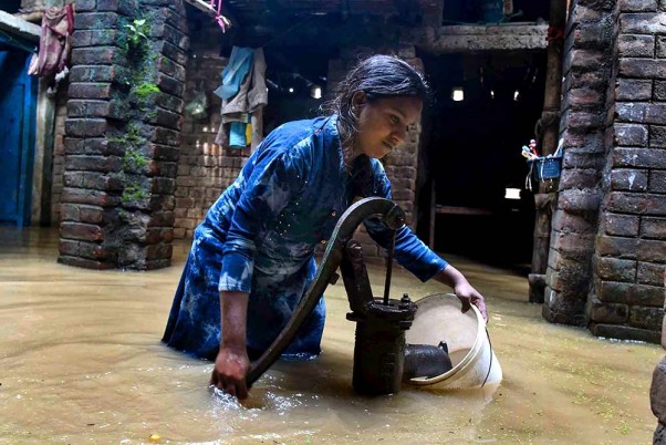 पटना के बेलदारी चाक के बाढ़ वाले इलाके में हैंडपंप से पीने योग्य पानी निकालती युवती